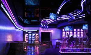 An industrial-style bar interior with neon lighting, concrete walls, and a warm, welcoming atmosphere.