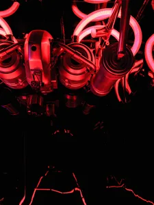 A dark, red-lit image of industrial equipment with tubing and metallic components.