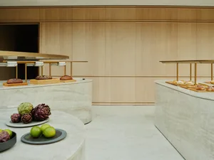 A modern restaurant interior with marble counters, bread, and fruit arrangements.