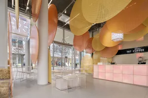 Interior of a modern coffee shop featuring a glass ceiling with geometric shapes.