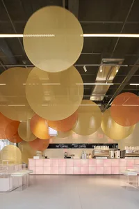 A modern coffee shop with large, circular glass pieces hanging from the ceiling.