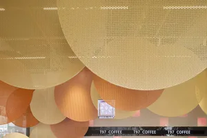 A modern coffee shop interior with metallic hexagonal shapes on the ceiling
