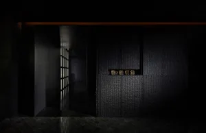 Modern restaurant interior with dark textured concrete walls and geometric light fixtures.