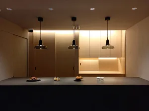 A modern kitchen with wooden cabinets and pendant lights hanging from the ceiling.
