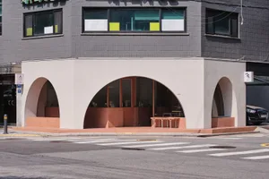 Modern, minimalist storefront with concrete and glass elements, located at a street corner.
