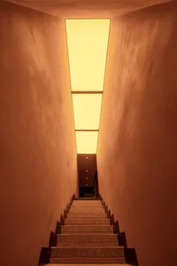 Modern staircase with concrete steps illuminated by a rectangular skylight
