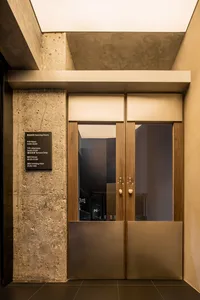 A modern entryway featuring wooden and concrete doors with glass windows.