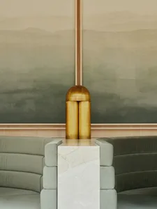 A modern living room with a brass table, marble coffee table, and green sofa.