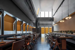 Modern restaurant interior with concrete, wood, and glass materials.