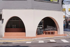 Modern storefront with arched glass doors made of concrete and glass.
