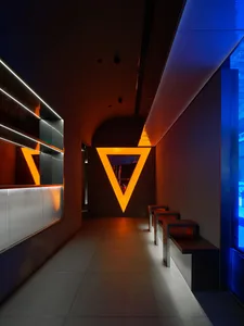 Modern, minimalist interior design featuring a triangular metal light fixture and sleek, minimalist furniture.