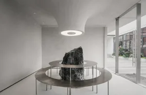 A minimalist lounge area with a metal base structure and a central stone feature.