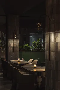 A modern minimalist restaurant interior featuring tiles and green plants