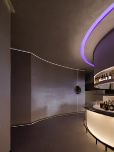 A contemporary bar with minimalist design, concrete walls, and illuminated circular lights.