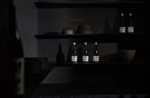 A modern kitchen with black shelves displaying bottles and ceramic bowls.