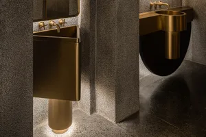 Modern industrial bathroom with metallic sinks and metallic fixtures.