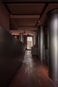 Image of a modern office entryway featuring metallic columns and a brick floor.