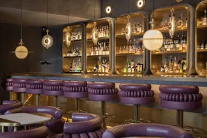 A sleek, modern restaurant bar featuring contemporary metal, leather, and glass elements.