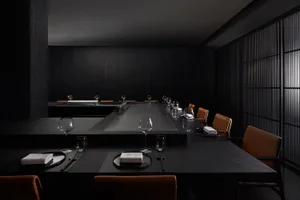 A modern restaurant interior featuring a sleek black stone dining area with minimalist decor and elegant table settings.