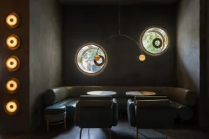 A minimalist coffee shop interior featuring leather seating, concrete walls, and wooden accents.