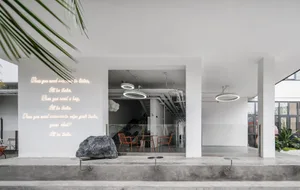 Modern restaurant with concrete tables and chairs, minimalist design, and neon lighting