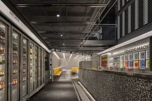 Modern industrial retail space featuring metal and glass counter and seating area.