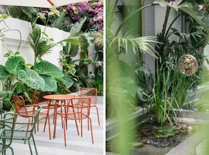Outdoor patio area with metal furniture surrounded by lush green plants and flowers.