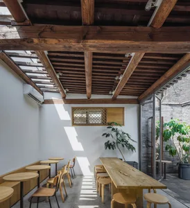 A cozy cafe interior featuring wooden furniture, including tables, chairs, and stools.