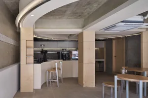 Industrial-style cafe interior with concrete walls and wooden furniture.