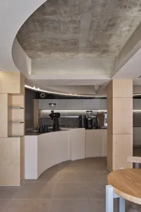 Industrial-style coffee shop kitchen featuring concrete walls, minimalist design, and modern coffee equipment.
