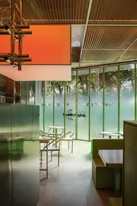 Modern cafe interior with glass walls and seating areas.