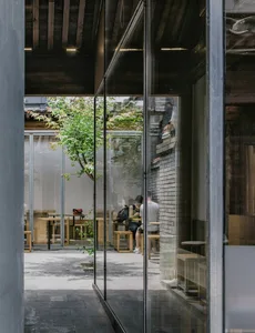 A modern coffee shop interior featuring glass walls and concrete flooring.