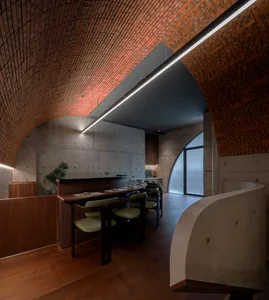 A modern restaurant dining room with concrete and brick walls and a circular arch.