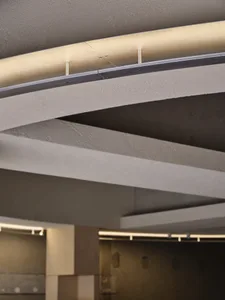 Modern interior design featuring a concrete ceiling with linear lighting and structural beams.
