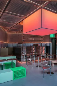 Modern restaurant with metal decor, green crates, and tall red square light fixture.