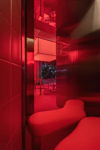 A minimalist interior design with red glass walls and furniture.