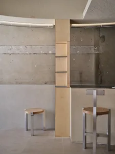 Minimalist concrete interior with stools and a wooden column