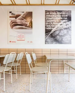 Modern restaurant interior featuring metal chairs and a tiled backsplash with concrete accents.