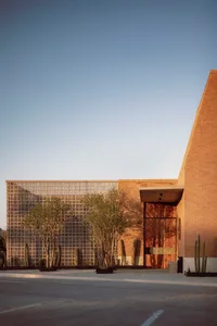 A modern building with a brick exterior, featuring large windows and a geometric design.