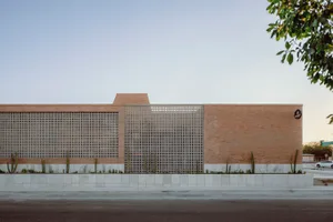 A modern brick building facade with a grid-patterned gate on the first floor and a flat roof.