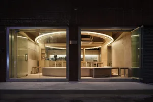 A modern restaurant with concrete and wooden elements, featuring open seating and a bar counter.