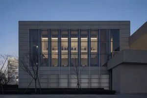 A modern office interior with large glass windows and concrete walls.