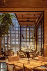 Indoor restaurant space featuring woven furniture with a wood frame and wooden ceiling beams.