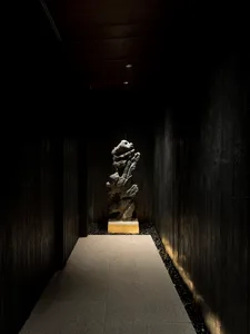 A sculpture exhibition hall with dark wooden walls and a sculpture on a pedestal in the center.