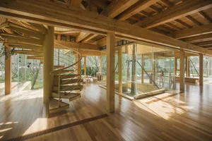 A residential interior design featuring a spiraling staircase with clear glass walls and wooden flooring.