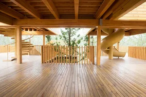 An indoor wooden playground with a spiral staircase and a slide surrounded by wooden fences.