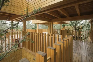 A modern playground with a wooden structure, featuring ramps and platforms.