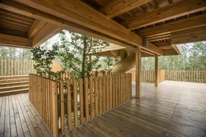 An outdoor wooden playground with a slide and trees