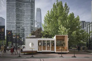 Glass-walled modern outdoor café with tables and chairs.