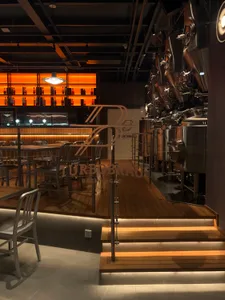 Contemporary brewery featuring steel brewing equipment and wooden bar seating.